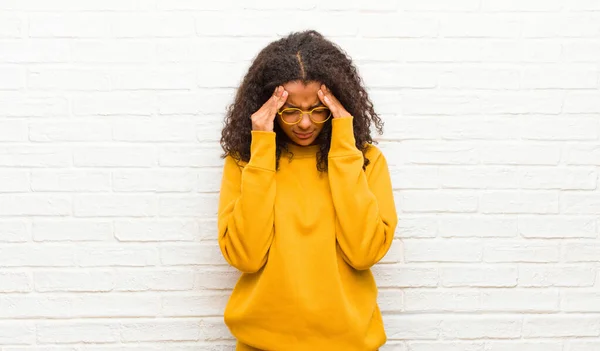 young black woman looking stressed and frustrated, working under pressure with a headache and troubled with problems against brick wall