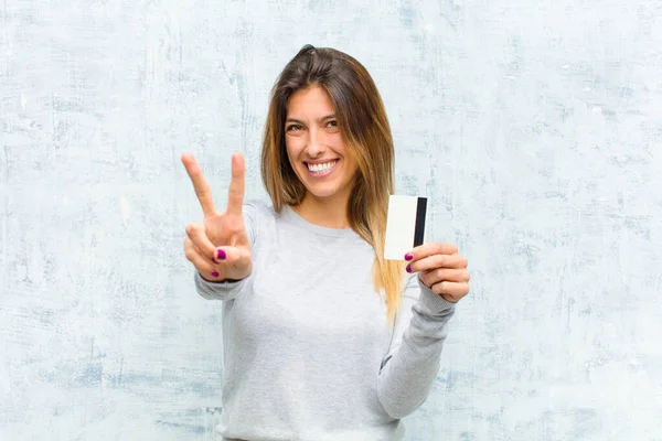 年轻漂亮的女人 带着信用卡靠着墙 — 图库照片