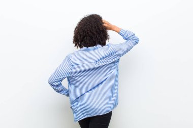 Genç, havalı, afro-amerikan bir kadın bilgisiz ve kafası karışık hissediyor, bir çözüm düşünüyor, eli kalçasında, diğeri kafasında, dikiz aynasından
