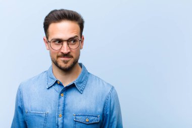 Genç yakışıklı adam merak ediyor, mutlu düşünceler ve fikirler düşünüyor, hayal kuruyor, kenarda yer arıyor.