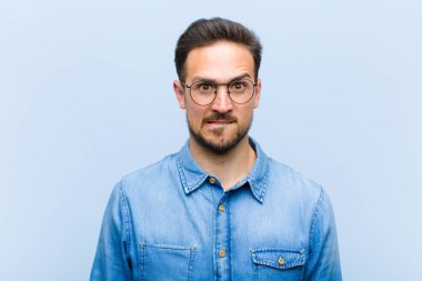 Şaşkın ve kafası karışmış genç bir adam gergin bir hareketle dudağını ısırıyor, sorunun cevabını bilmiyor.