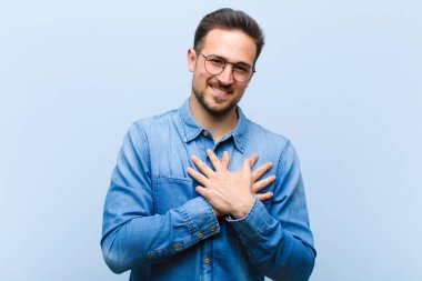 Genç yakışıklı adam romantik, mutlu ve aşık, neşeyle gülümsüyor ve kalbe yakın el ele tutuşuyor.