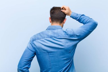 Genç yakışıklı bir adam bilgisiz ve kafası karışık hissediyor, bir çözüm düşünüyor, eli kalçasında, diğeri kafasında, dikiz aynasından.