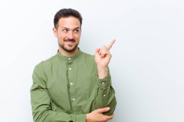 Genç yakışıklı adam mutlu bir şekilde gülümsüyor ve yan bakıyor, merak ediyor, düşünüyor ya da bir fikri var.