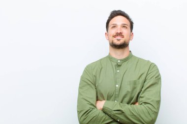 Genç yakışıklı adam mutlu, gururlu ve umutlu, merak ediyor ya da düşünüyor, çapraz kollarla boşluğu dolduruyor.