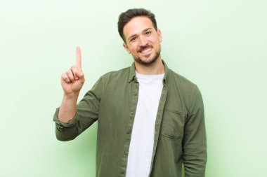 Genç yakışıklı adam gülümsüyor ve arkadaş canlısı görünüyor, bir numara ya da ilk eli önde, geriye doğru sayıyor.