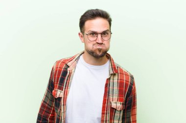 Aptal, çılgın, şaşkın bir ifadeyle genç yakışıklı adam, yanakları şişmiş, doldurulmuş, şişman ve yemekle dolu.