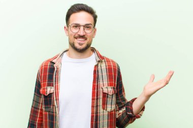 Genç yakışıklı adam kendini mutlu, şaşırmış ve neşeli hissediyor. Pozitif bir tavırla gülümsüyor. Bir çözüm ya da fikir buluyor.