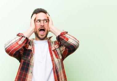 Genç yakışıklı adam mutlu, heyecanlı ve şaşırmış hissediyor, iki eli yüzü yana bakıyor.