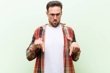 Genç yakışıklı adam şok olmuş, ağzı açık ve şaşkın, inançsızlık ve şaşkınlık içinde bakıyor ve onu işaret ediyor.