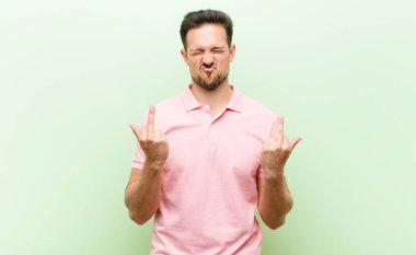 Genç yakışıklı adam kışkırtıcı, agresif ve müstehcen hissediyor. İsyankar bir tavırla orta parmağını hareket ettiriyor.