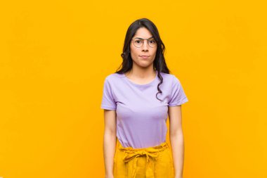 Genç, güzel, Latin bir kadın. Kafası karışık ve kuşkulu. Turuncu duvara karşı karar vermeye çalışıyor.