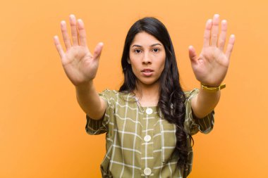 Genç ve güzel İspanyol bir kadın ciddi, mutsuz, kızgın ve hoşnutsuz görünüyor. Girmeyi yasaklıyor ya da her iki avuç içi de kahverengi duvara yaslıyken dur diyor.