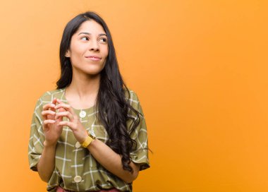 Genç ve güzel İspanyol kadın gururlu, haylaz ve kibirli hissederken şeytani bir plan kuruyor ya da kahverengi duvara karşı bir numara düşünüyor.