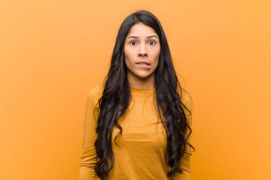 Genç, güzel İspanyol bir kadın kafası karışmış ve kafası karışmış görünüyor. Sinirli bir hareketle dudağını ısırıyor. Kahverengi duvardaki sorunun cevabını bilmiyor.