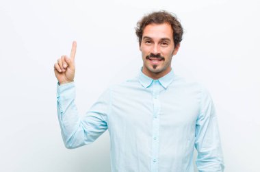 Genç yakışıklı adam neşeyle ve mutlulukla gülümsüyor, tek eliyle yukarıya doğru uzayı beyaz duvara kopyalıyor.