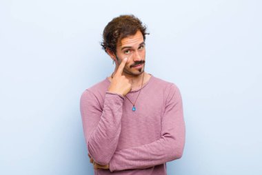 Genç yakışıklı adam sana göz kulak oluyor, güvenmiyor, izliyor ve tetikte bekliyor ve düz duvara karşı tetikte bekliyor.