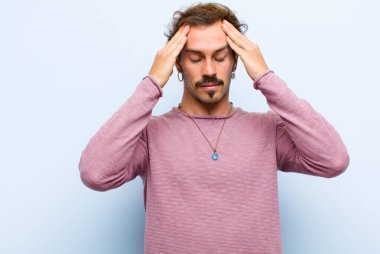 Genç yakışıklı adam konsantre, düşünceli ve ilham verici görünüyor, beyin fırtınası yapıyor ve elleri alnında düz duvara yaslanmış hayal ediyor.