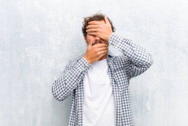 Genç yakışıklı adam kameraya hayır diyen iki eliyle yüzünü kapatıyor! Resimleri reddetmek ya da düz duvara izole edilmiş resimleri yasaklamak