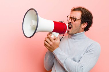 Pembe düz duvara karşı megafonlu genç yakışıklı adam.