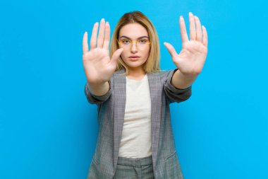 Genç, güzel, sarışın kadın ciddi, mutsuz, kızgın ve hoşnutsuz görünüyor. Girmeyi yasaklıyor ya da iki avuç içi de düz duvara yaslıyken dur diyor.