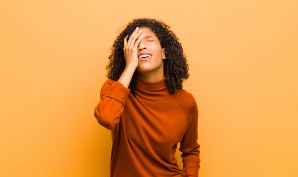 若いかなり黒い女性は眠い 退屈し あくびをしていて 頭痛と片手で顔の半分をオレンジの壁に覆います — ストック写真