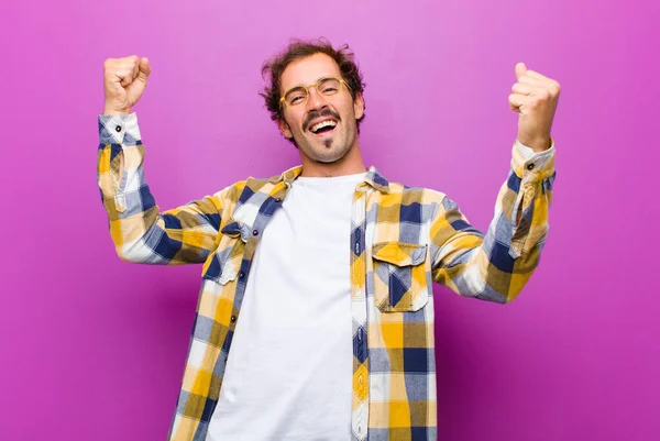 若いハンサムな男が意気揚々と叫んで興奮して幸せそして驚きの勝者のように見えます紫色の壁に対してお祝い — ストック写真
