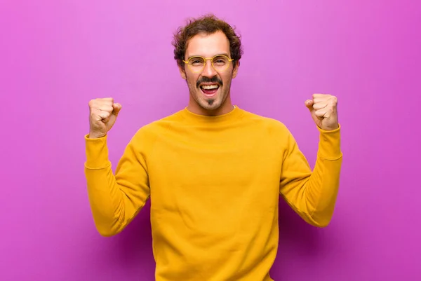 若いハンサムな男は幸せを感じます 正と成功 勝利を祝う 成果や紫色の壁に対する幸運 — ストック写真