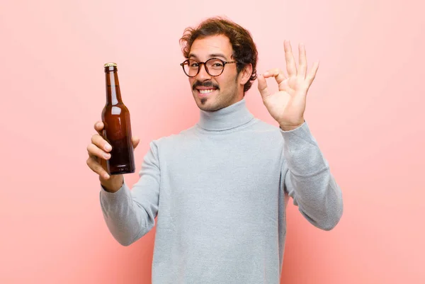 年轻英俊的男子在粉红的平板墙上与啤酒共舞 — 图库照片