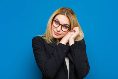 Genç ve güzel sarışın kadın aşık ve sevimli görünüyor, sevimli ve mutlu, romantik bir şekilde gülümsüyor.