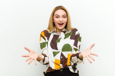 Genç sarışın kadın kendini mutlu, şaşkın, şanslı ve şaşırmış hissediyor. Beyaz duvara karşı inanılmaz.