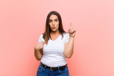 Genç ve güzel İspanyol kadın gururlu ve şaşırmış hissediyor, kendine güvenerek, pembe duvara karşı başarılı olduğunu hissediyor.