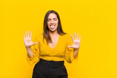 Genç ve güzel bir bayan gülümsüyor ve arkadaş canlısı görünüyor, onuncu ya da onuncu numarayı gösteriyor, elini öne uzatmış, turuncu duvara karşı geriye doğru sayıyor.