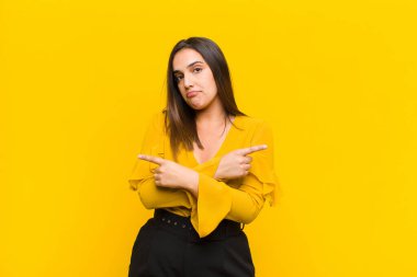 Kafası karışmış, kafası karışmış, güvensiz ve zıt yönleri işaret eden genç, güzel bir kadın.