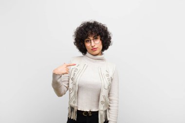 Genç, güzel afro kadın gururlu, kendinden emin ve mutlu görünüyor, gülümsüyor ve kendini işaret ediyor ya da bir numaralı işareti yapıyor.