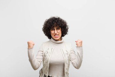 Genç, güzel afro kadın sinirli bir ifadeyle bağırıyor ya da yumruklarıyla başarıyı kutluyor.