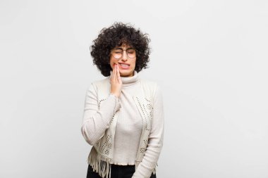 Genç, güzel afro kadın, yanağını tutuyor ve acı veren diş ağrısı çekiyor. Hasta, sefil ve mutsuz hissediyor, dişçi arıyor.