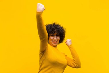 Genç, güzel afro kadın muzaffer bir şekilde bağırıyor. Heyecanlı, mutlu ve şaşırmış görünüyor. Kutlama yapıyor.