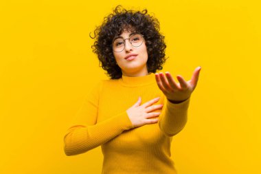 Genç, güzel, afro bir kadın mutlu ve aşık, bir eli kalbinin yanında, diğer eli önde uzanmış.