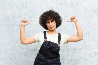 Genç, güzel afro kadın gururlu, kibirli ve kendinden emin, tatmin olmuş ve başarılı görünüyor, kendini işaret ediyor.