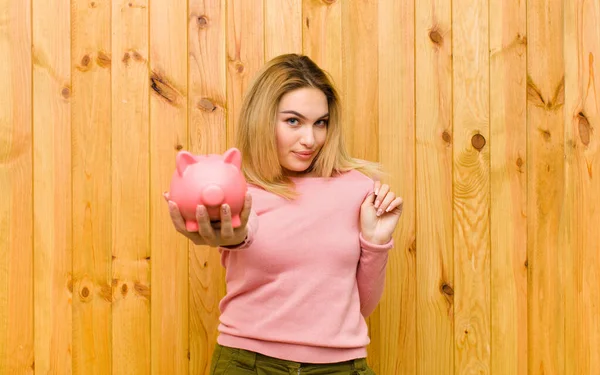 Jovem Mulher Loira Bonita Com Banco Porquinho Contra Parede Madeira — Fotografia de Stock