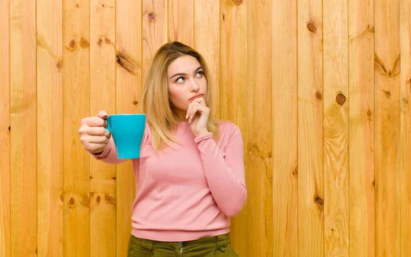 Genç Güzel Sarışın Bir Kadın Elinde Kahve Fincanı Tahta Duvara — Stok fotoğraf