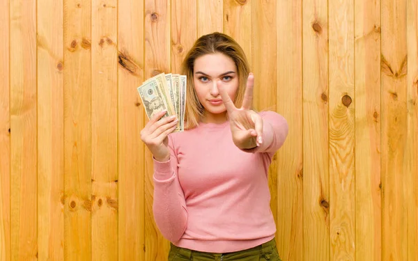木製の壁にドル紙幣の若いかなりブロンドの女性 — ストック写真
