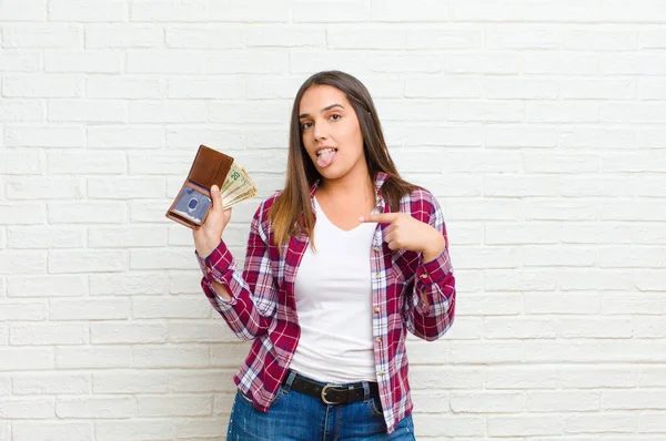 young pretty woman with a wallet against brick wall texture