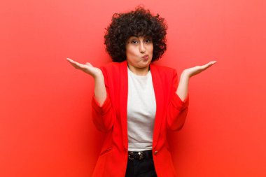 Genç, güzel afro kadın şaşkın ve şaşkın hissediyor, şüpheci, ağırlıklı ya da farklı seçenekleri komik bir ifadeyle seçiyor.