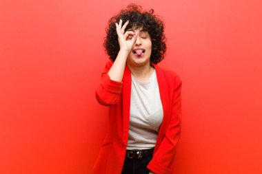 Genç, güzel afro kadın mutlu bir şekilde gülümsüyor, şaka yapıyor ve gözetleme deliğinden bakıyor, sırları gözetliyor.