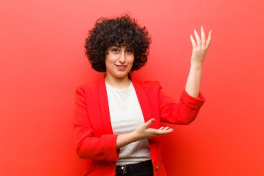 Genç, güzel afro kadın gururla ve kendinden emin bir şekilde gülümsüyor, mutlu ve tatmin olmuş hissediyor ve fotokopi alanında bir konsept gösteriyor.