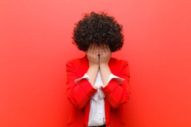 Genç, güzel afro kadın üzgün, hayal kırıklığına uğramış, gergin ve depresif, iki eliyle yüzünü kaplayan, ağlayan