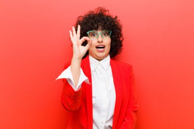 Genç, güzel afro kadın kendini başarılı ve tatmin olmuş hissediyor, ağzı açık gülümsüyor, elle imza atıyor.