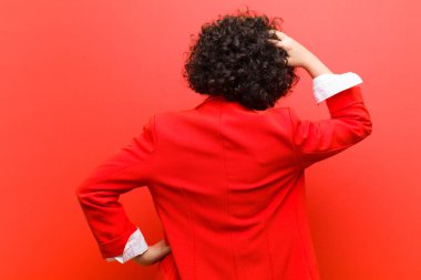 Genç, güzel, afro bir kadın bilgisiz ve kafası karışık, bir çözüm düşünüyor, eli kalçasında, diğeri kafasında, dikiz aynasından.